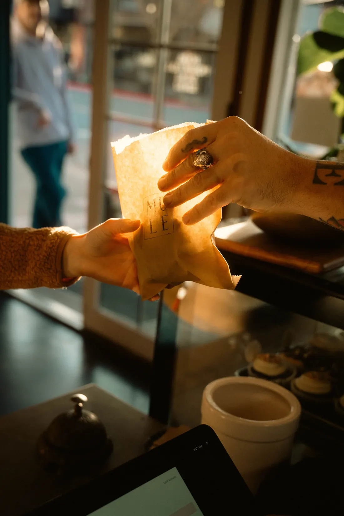 A café team member handing a takeaway bag to a customer